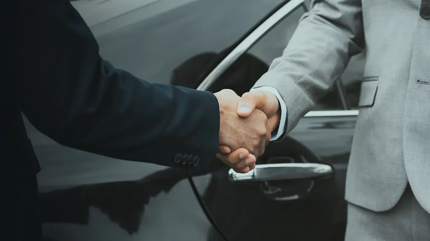Poignée de main devant la portière d'une voiture avec chauffeur