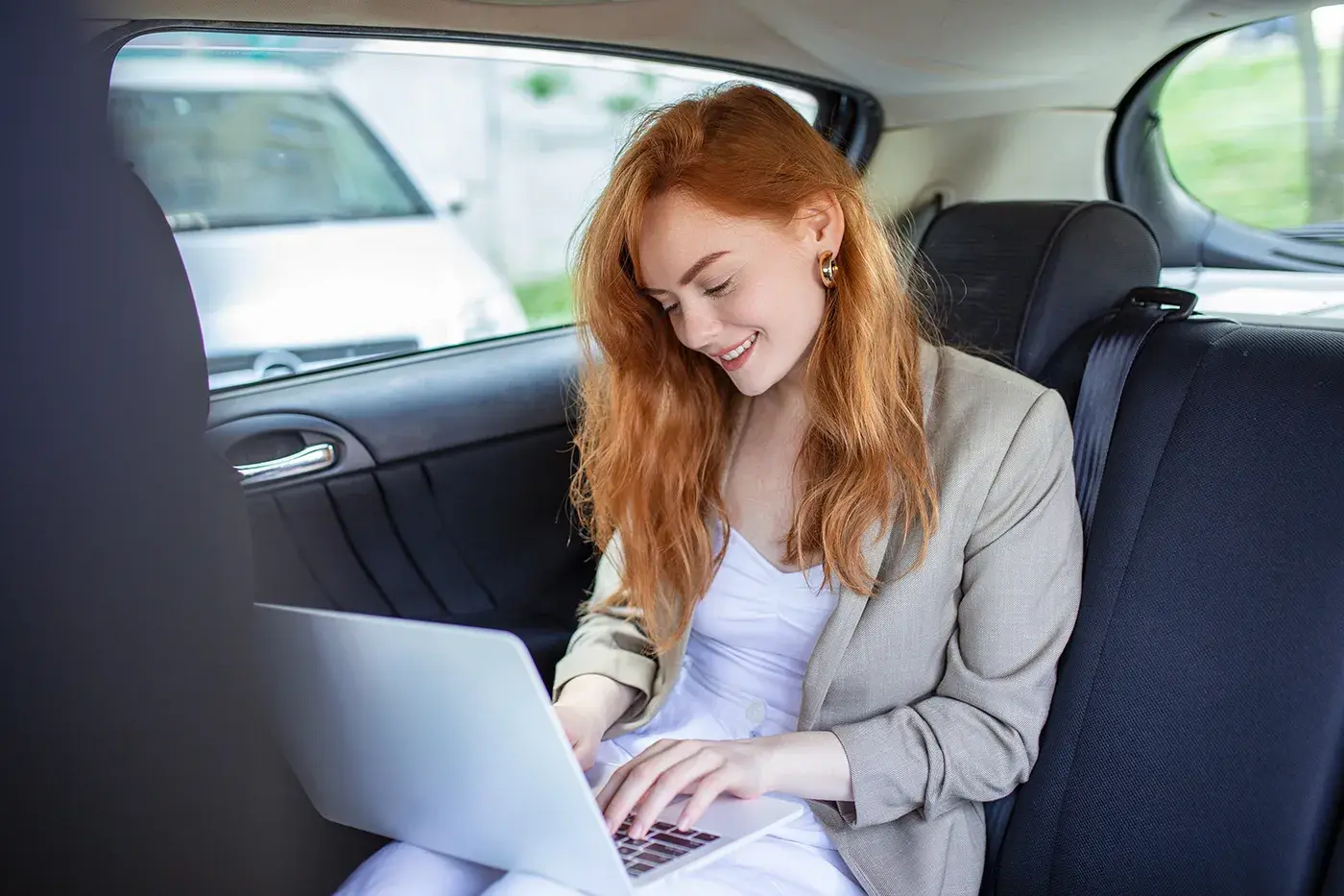 Passagère souriante installée à l'arrière d'une voiture avec chauffeur
